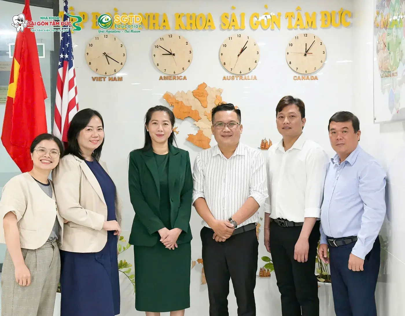 Đại diện SGTD Education và Gerimmi chụp ảnh lưu niệm trước bức tường Tập đoàn Nha khoa Sài Gòn Tâm Đức