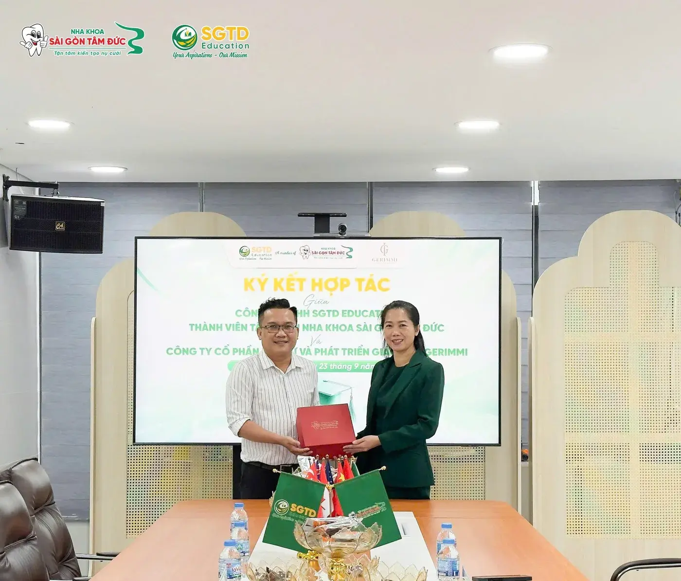 Đại diện hai đơn vị trao quà lưu niệm trước màn hình lễ ký kết hợp tác
