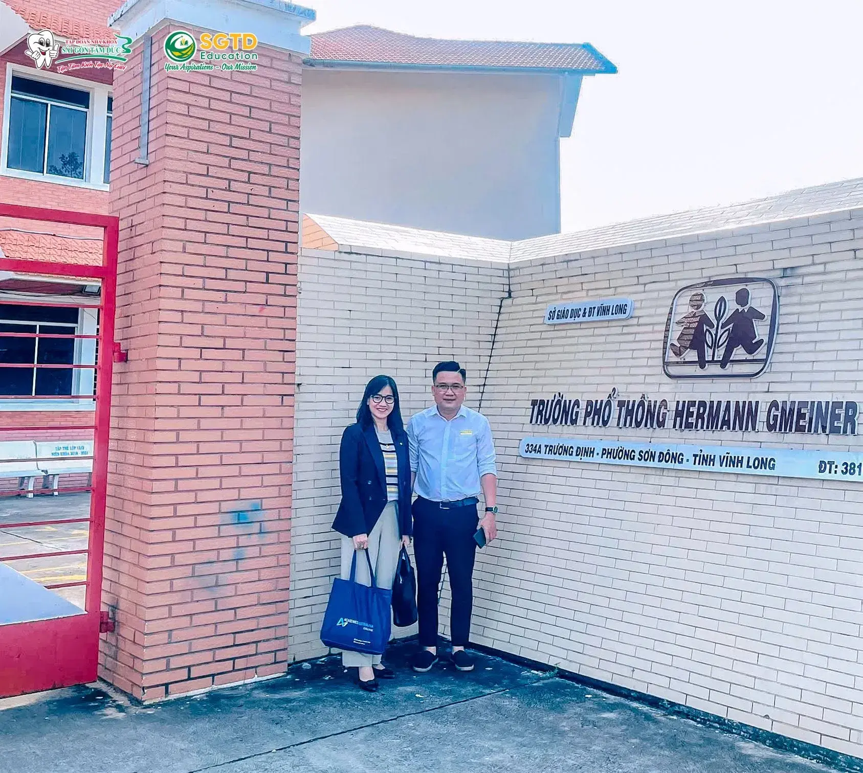 Đoàn công tác trước bảng tên Trường Phổ thông Hermann Gmeiner